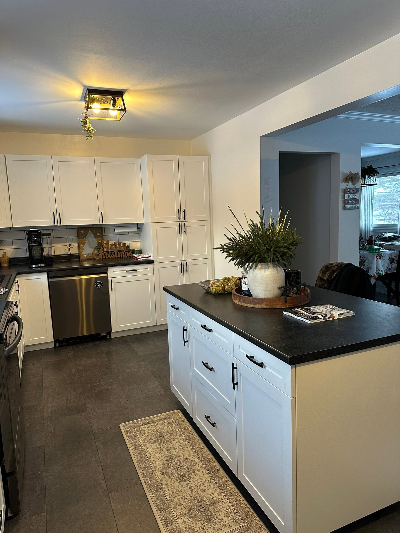Completed kitchen with white cabinetry, a black-topped island and new flooring